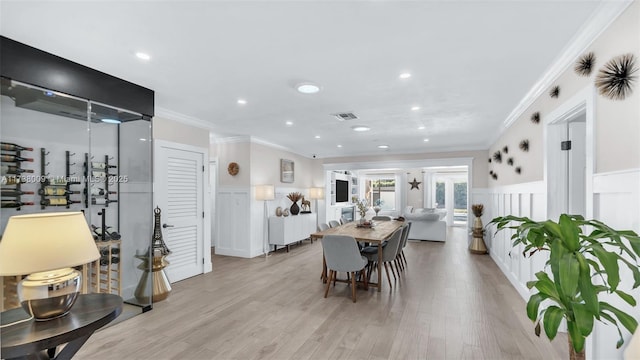 dining space with crown molding and light wood-type flooring