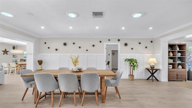 dining area with an inviting chandelier, crown molding, and light wood-type flooring