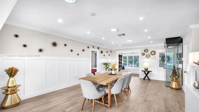 dining space with crown molding and light hardwood / wood-style floors