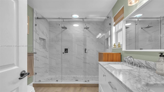 bathroom featuring vanity, a shower with shower door, and toilet