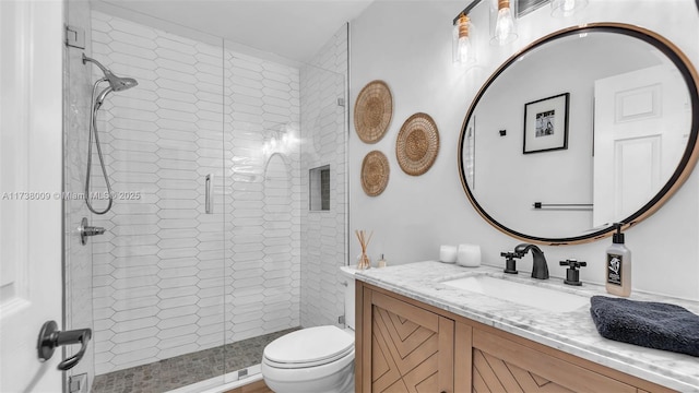 bathroom with vanity, a shower with shower door, and toilet