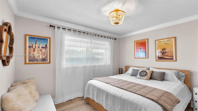 bedroom featuring ornamental molding, a chandelier, and light hardwood / wood-style flooring