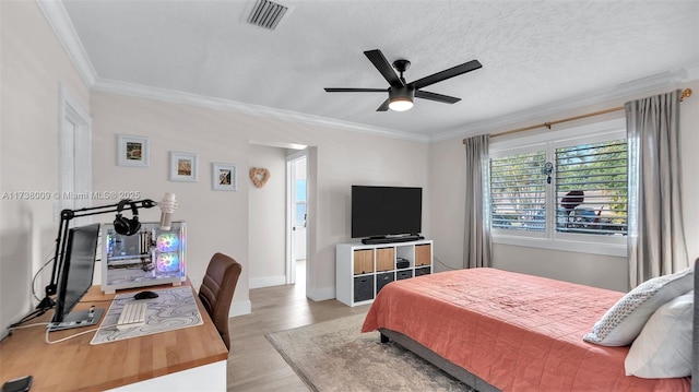 bedroom with ceiling fan, light hardwood / wood-style flooring, ornamental molding, and a textured ceiling