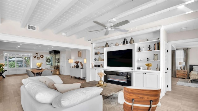 living room featuring beamed ceiling, ceiling fan, built in shelves, and light hardwood / wood-style flooring