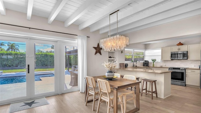 dining room featuring sink, light hardwood / wood-style flooring, an inviting chandelier, beam ceiling, and french doors