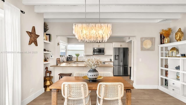 dining area featuring beamed ceiling, an inviting chandelier, and light hardwood / wood-style floors