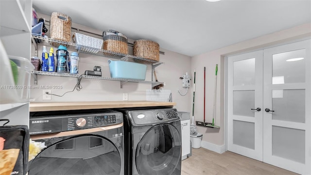 clothes washing area with light hardwood / wood-style floors, independent washer and dryer, and french doors