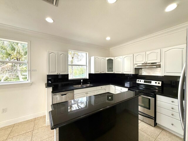 kitchen featuring dark countertops, a center island, stainless steel appliances, under cabinet range hood, and a sink