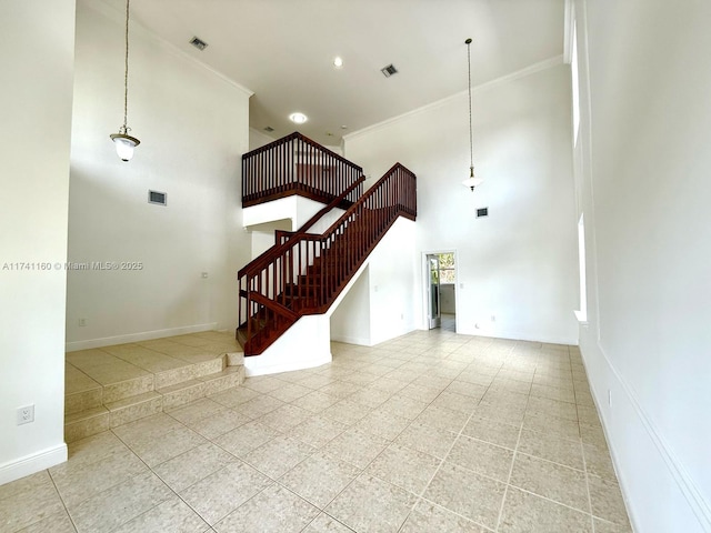 living area featuring visible vents, a towering ceiling, ornamental molding, baseboards, and stairs