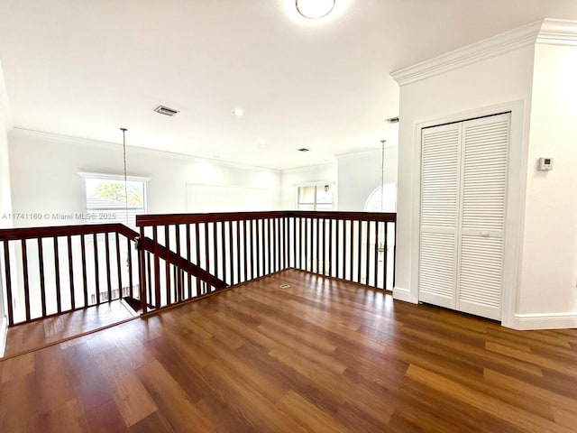 corridor featuring visible vents, baseboards, dark wood finished floors, and crown molding