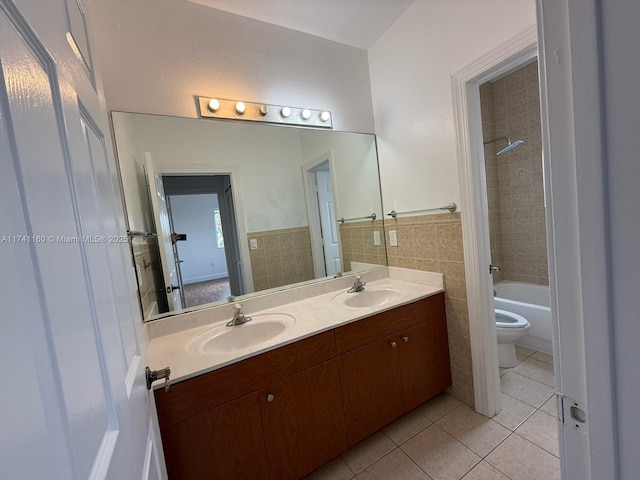 bathroom featuring tile walls, double vanity, toilet, a sink, and tile patterned flooring