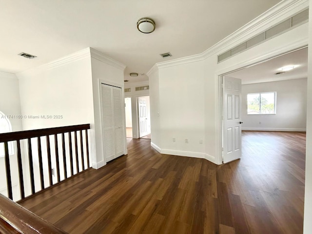 hall with ornamental molding, dark wood finished floors, visible vents, and baseboards