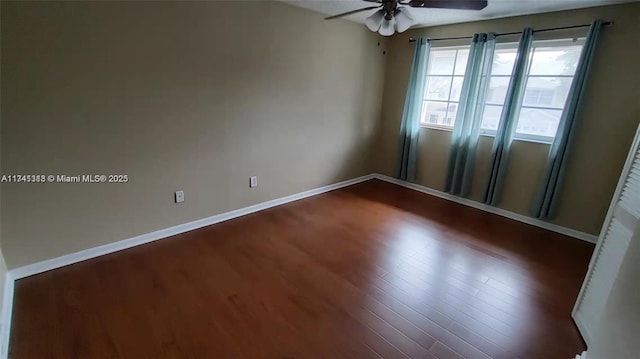 empty room with ceiling fan and dark hardwood / wood-style flooring