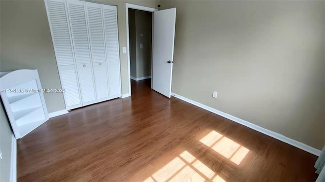 unfurnished bedroom with dark hardwood / wood-style flooring and a closet