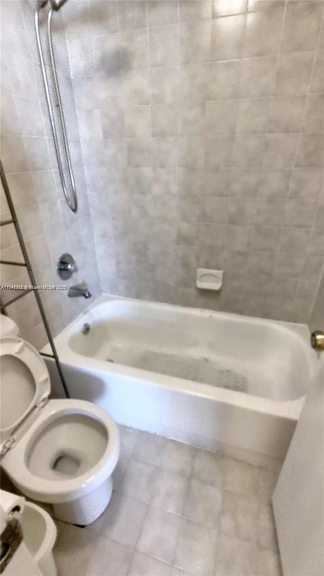 bathroom featuring tiled shower / bath and toilet