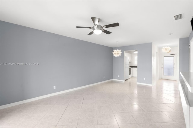 spare room featuring light tile patterned floors and ceiling fan with notable chandelier