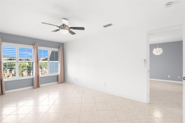 tiled empty room with ceiling fan with notable chandelier