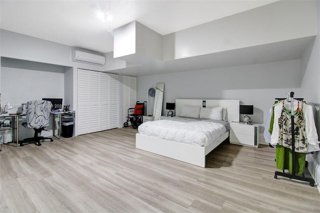 bedroom featuring light hardwood / wood-style flooring and a wall unit AC