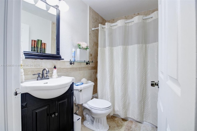 bathroom featuring vanity, toilet, and tile walls