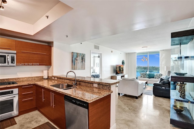 2681 N Flamingo Rd Unit 605S, Sunrise, FL 33323 - kitchen featuring stainless steel appliances, a sink, a peninsula, open floor plan, and brown cabinets