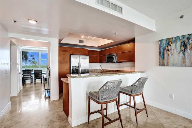 2681 N Flamingo Rd Unit 605S, Sunrise, FL 33323 - kitchen with appliances with stainless steel finishes, a peninsula, baseboards, a raised ceiling, and brown cabinetry