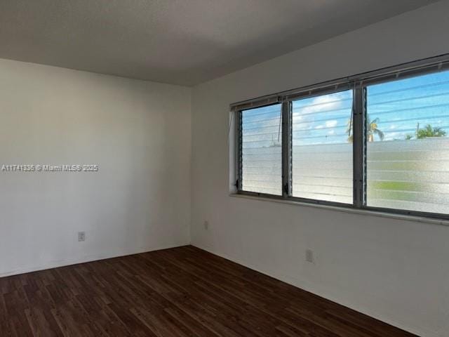 empty room with a healthy amount of sunlight and dark hardwood / wood-style floors