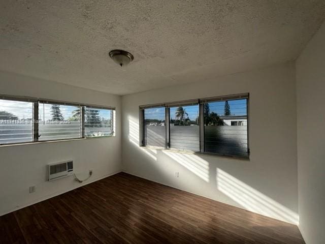 unfurnished room featuring a textured ceiling, wood-type flooring, and a wall mounted AC