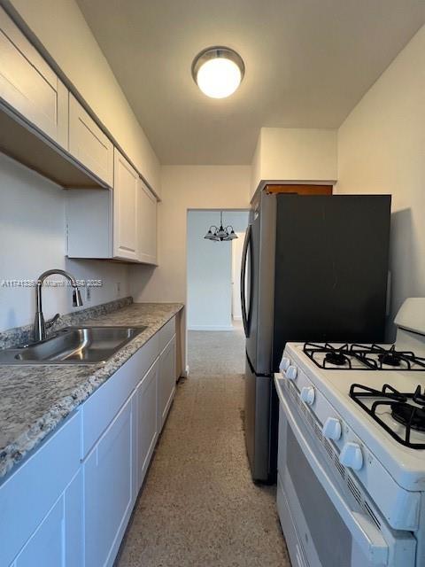 kitchen featuring white cabinetry, sink, a notable chandelier, and white gas stove