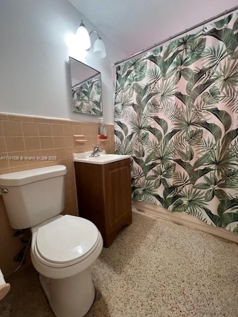 bathroom featuring vanity, tile walls, and toilet