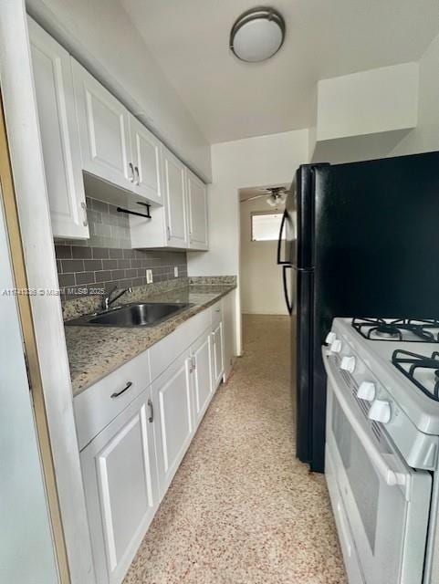 kitchen with stone countertops, sink, white cabinets, decorative backsplash, and white gas stove