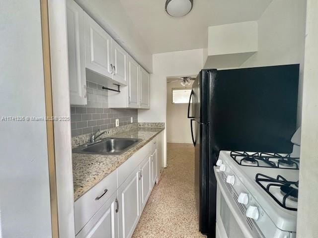 kitchen featuring sink, white cabinetry, light stone countertops, white gas range, and decorative backsplash