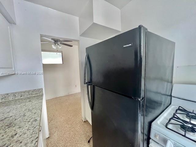 kitchen with white cabinetry, black refrigerator, ceiling fan, and white gas range oven