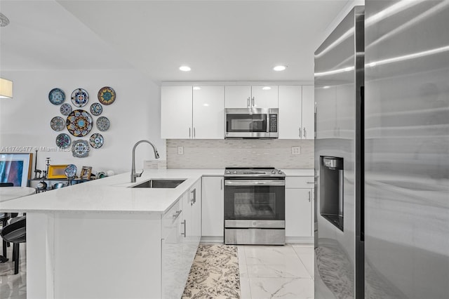 kitchen with white cabinetry, appliances with stainless steel finishes, sink, and kitchen peninsula