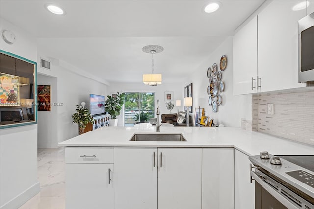 kitchen featuring stainless steel appliances, kitchen peninsula, sink, and white cabinets