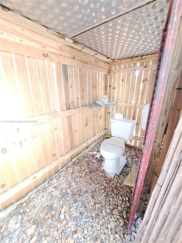 bathroom with wooden walls and toilet