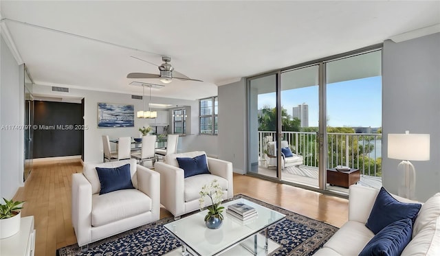 living room featuring expansive windows, ornamental molding, wood-type flooring, and plenty of natural light