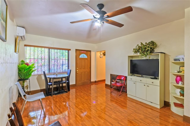 living room with hardwood / wood-style flooring, a wall unit AC, and ceiling fan