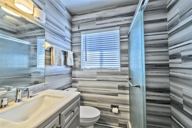 bathroom featuring vanity, toilet, and tile walls