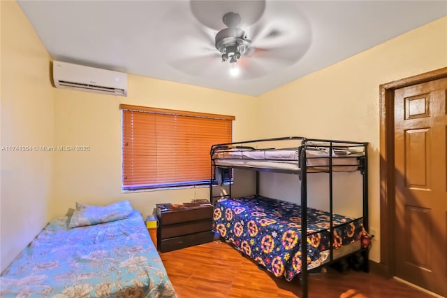 bedroom with hardwood / wood-style flooring, a wall mounted AC, and ceiling fan