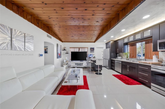 living room featuring light tile patterned floors, vaulted ceiling, wooden ceiling, and sink