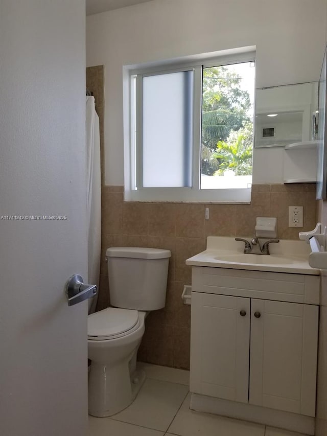 bathroom featuring vanity, tile patterned floors, tile walls, and toilet