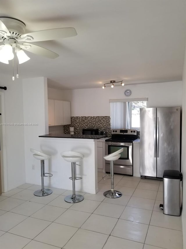 kitchen with white cabinetry, a kitchen bar, tasteful backsplash, and appliances with stainless steel finishes