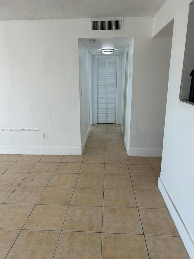 hallway with light tile patterned floors and a textured ceiling