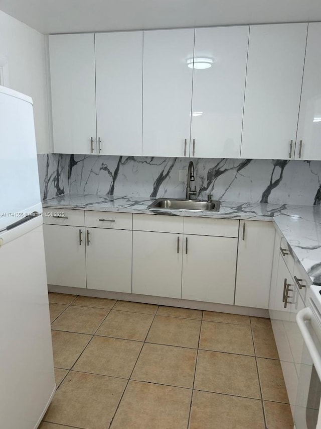 kitchen with white cabinetry, sink, white fridge, and light tile patterned floors