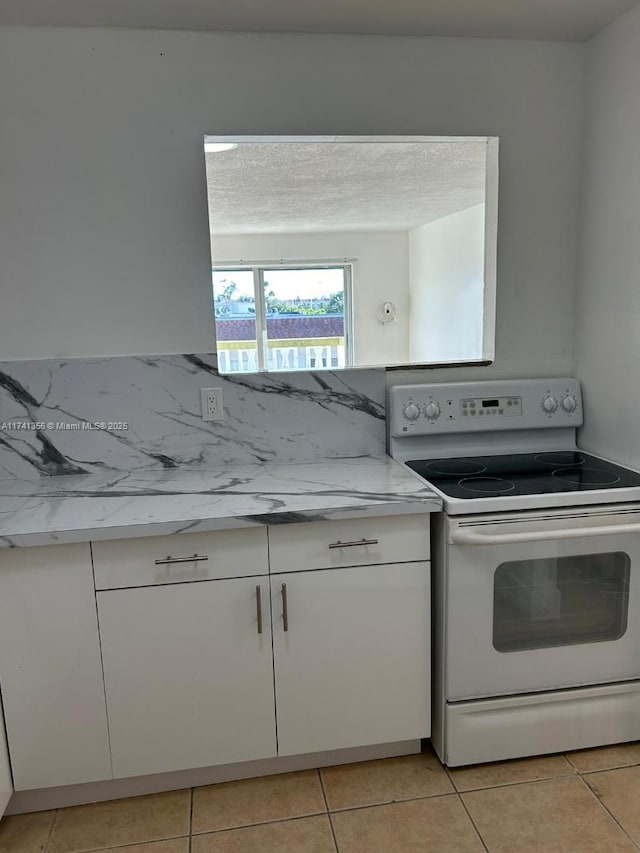 kitchen with white cabinetry, light tile patterned floors, white electric range, and a textured ceiling