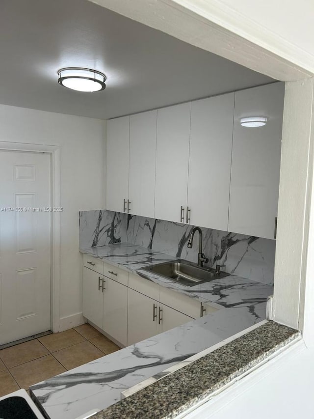 kitchen featuring light tile patterned flooring, sink, white cabinetry, tasteful backsplash, and stone countertops