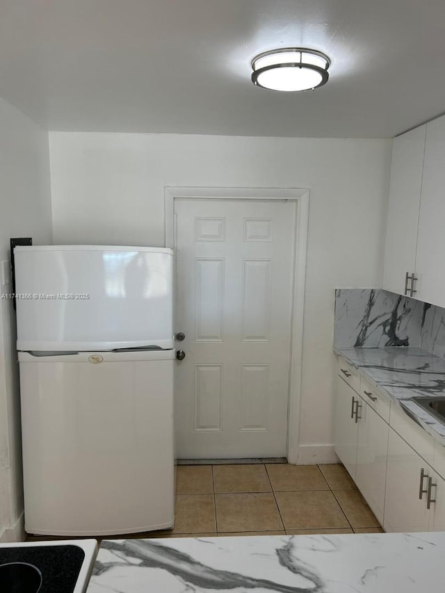 kitchen with white cabinetry, backsplash, and white fridge