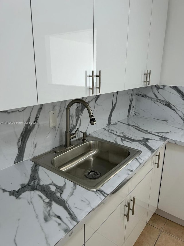 interior details with sink, white cabinets, and backsplash