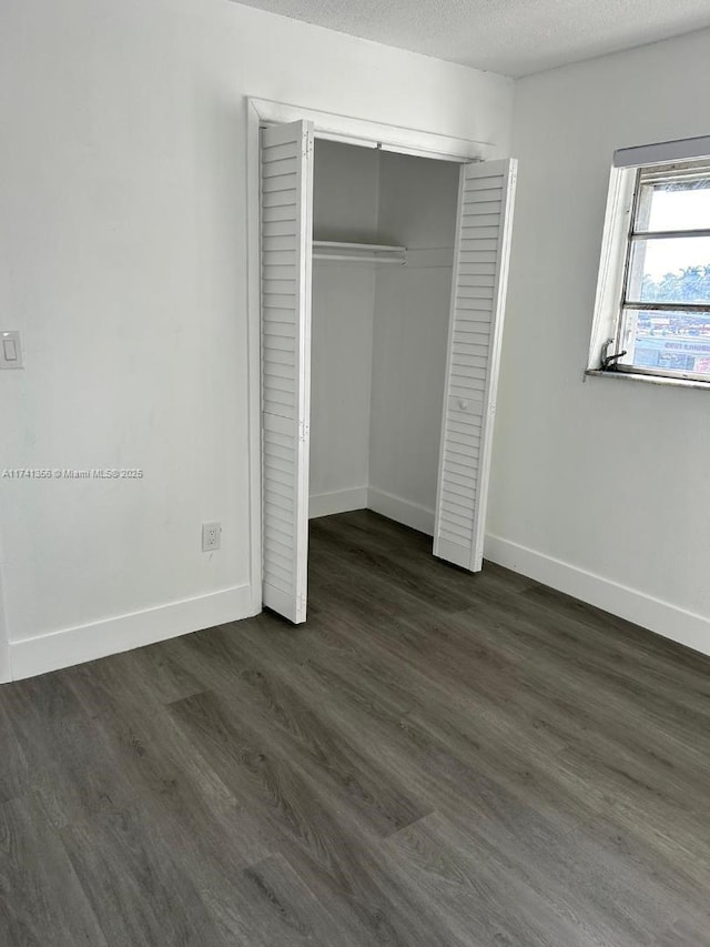 unfurnished bedroom featuring dark wood-type flooring, a closet, and a textured ceiling