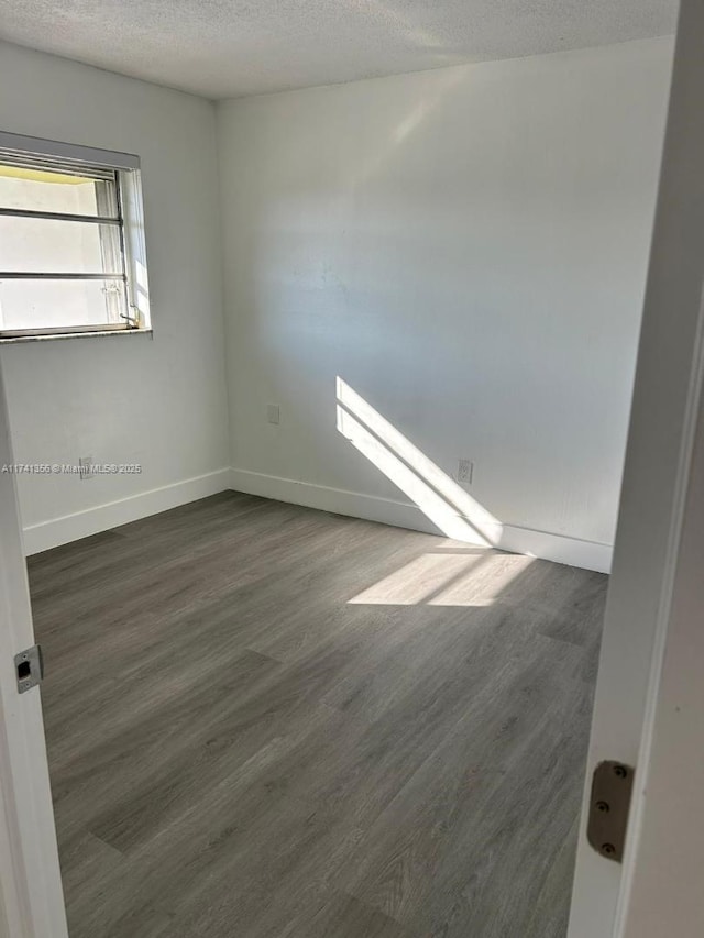 empty room featuring dark wood-type flooring and a textured ceiling